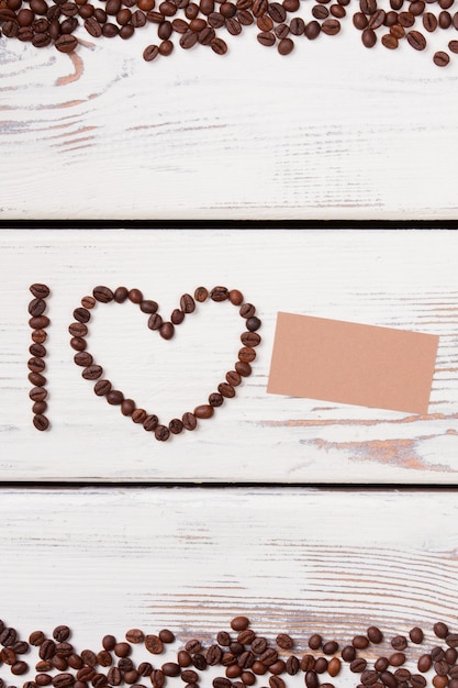 Letter I and heart frame shaped coffee beans with blank paper. I love copyspace. Free space for text.