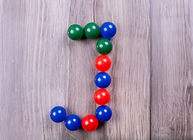 The letter j made of colorful balls on a wooden table