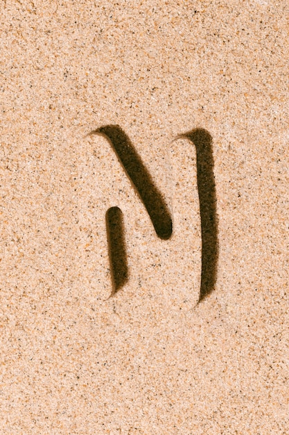 Letter N of the sand isolated on the beach sand concept of summer alphabet