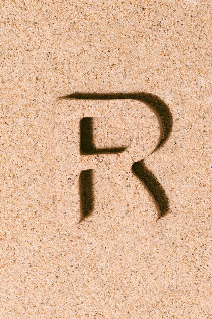 Letter R of the sand isolated on the beach sand concept of summer alphabet