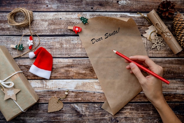 Letter to santa claus, christmas wishlist on wooden background among holiday
decoration