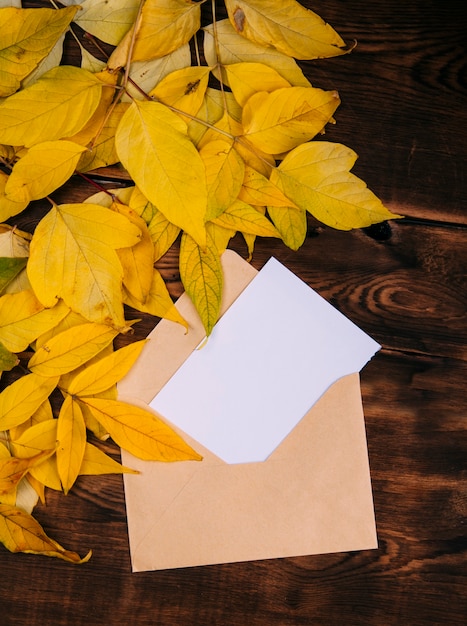 letter with blank white paper decorated with yellow leaves on wooden background