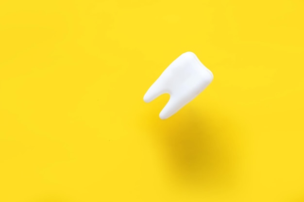 Levitating tooth on a yellow background. dentistry advertising concept.