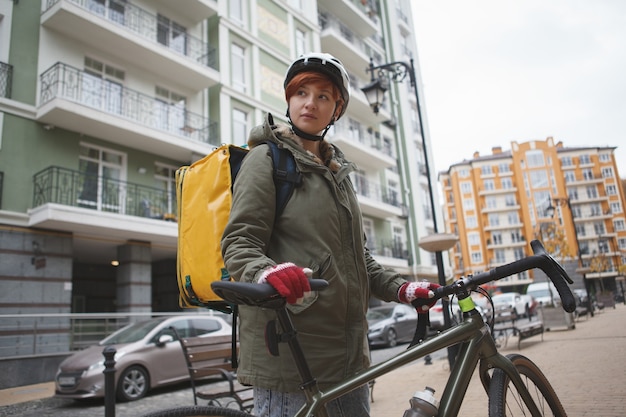 Lfemale delivery courier walking with her bicycle