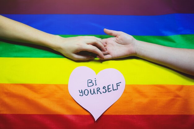 Lgbt community colorful flag. Two women's hands on rainbow background. Lesbian and gay problems. Legalization of marriage for couples with homosexual orientation.