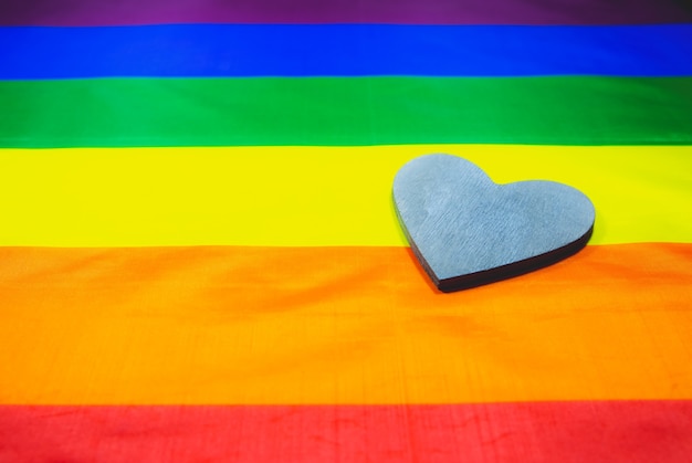 Photo lgbt community colorful flag. wooden heart on rainbow background. lesbian and gay problems. legalization of marriage for couple with homosexual orientation.