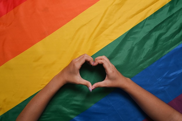 LGBT lesbian couple hands took the shape of a heart over rainbow LGBT flag Concept of LGBT pride