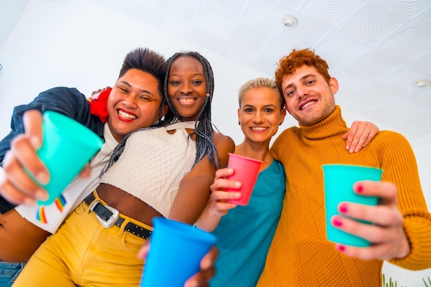 LGBT pride lgbt rainbow flag portrait of group of friends dancing and toasting with glasses in a house at party