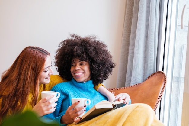 Lgtbi couple of young girls sharing a cup of hot coffee in an afternoon at home