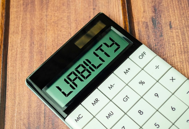 Liability word on calculator display on wooden background