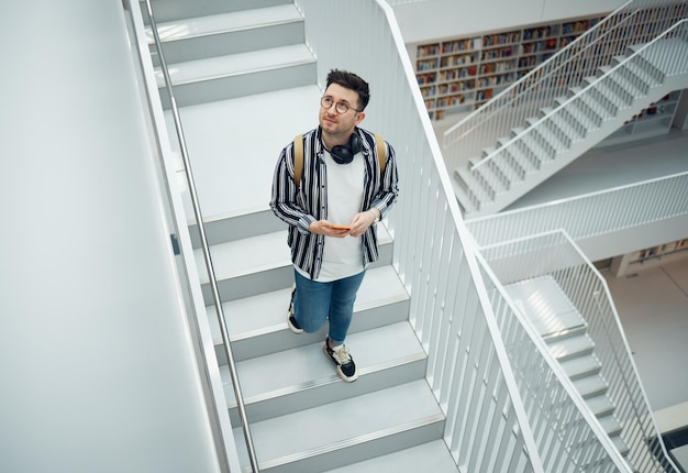 Library search geek student or intelligent man for phd research creative vision and knowledge in university College stairs above and person thinking of books for education scholarship or study