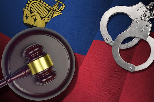 Liechtenstein flag with judge mallet and handcuffs in dark room Concept of criminal and punishment background for judgement topics