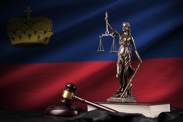 Liechtenstein flag with statue of lady justice constitution and judge hammer on black drapery Concept of judgement and guilt