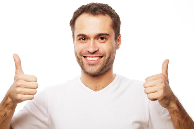 Life style  and people concept: Happy handsome man wearing white t-shirt showing thumbs up over isolated background