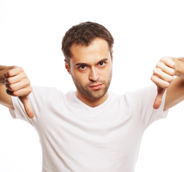 Life style  and people concept: young casual man making the thumbs down negative hand sign on white background