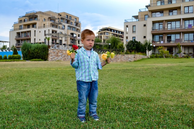 Life style portrait redhaired boy 34 years old in a park with flowers cheerful childhood summer vacation holidays