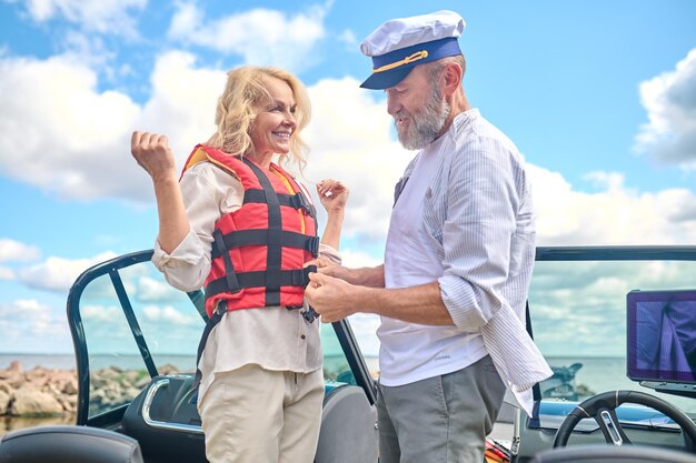 Photo life vest. a man in helping a blonde woman to put on the life vest