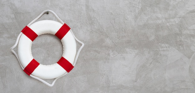 Lifebuoy on concrete wall background.