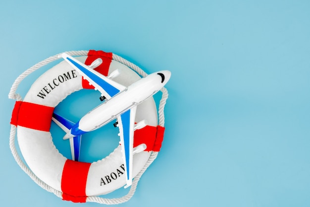 Lifebuoy and model of airplane on blue background. Summer or vacation concept. Copy space.