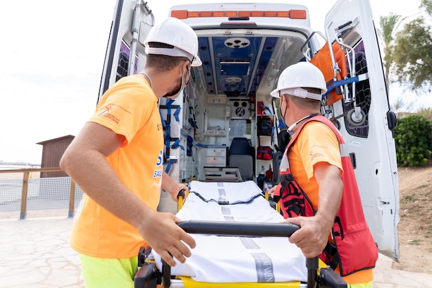 Lifeguard with uniform using a stretcher from an ambulance