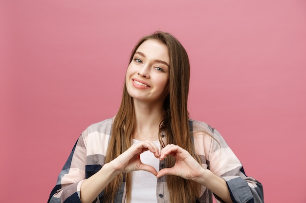 Lifestyle Concept: Beautiful attractive woman in white shirt making a heart symbol with her hands