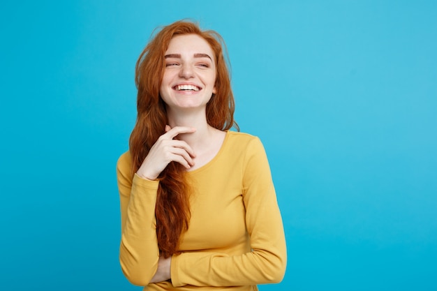 Lifestyle concept - Close up Portrait young beautiful attractive ginger red hair girl playing with her hair with shyness. Blue Pastel Background. Copy space.