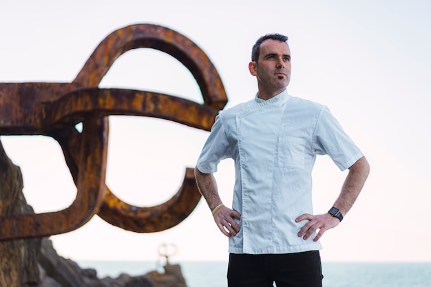 Lifestyle of a cook, a young man in a white apron in a photo on the coast