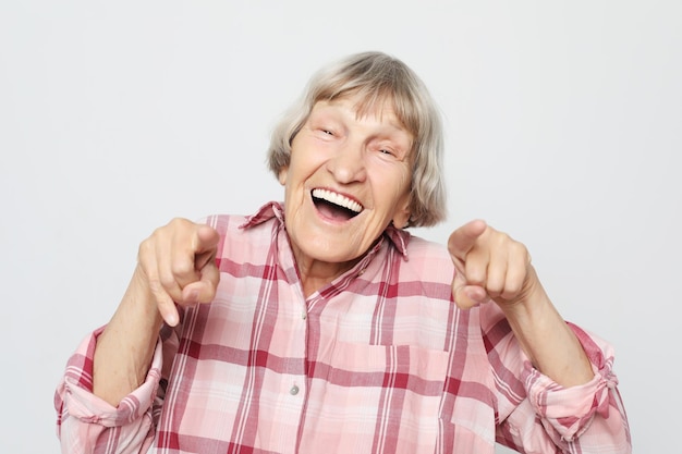 Lifestyle emotion and people concept Aged grandmother with shocked face Portrait of grandmother with pink shirt