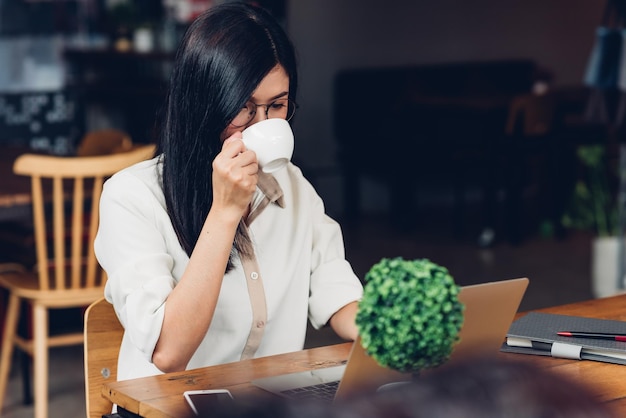 Lifestyle freelance working woman with laptop computer, he drinking coffee in coffee cafe shop