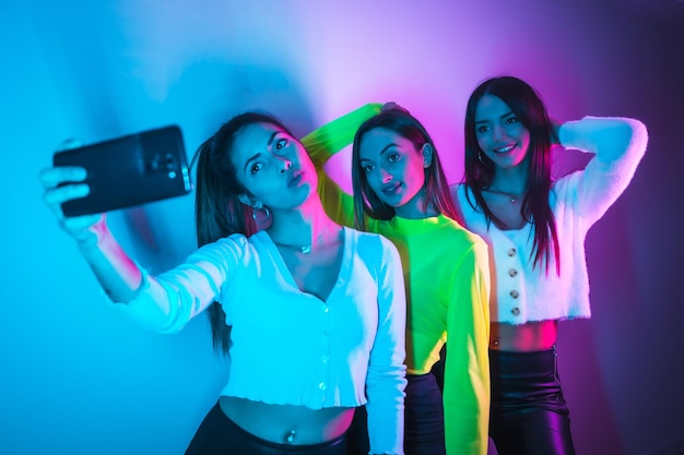 Lifestyle of friends partying in a nightclub with blue and pink neon lights taking a selfie with the phone