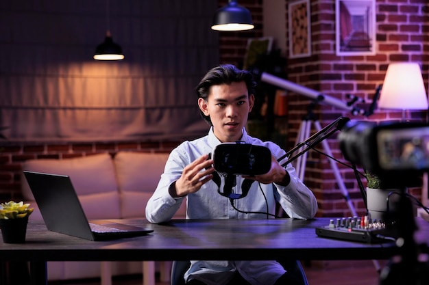 Lifestyle influencer filming product review with vr glasses, broadcasting live podcast on camera. Recording virtual reality goggles recommendation on livesteam, creating social media channel content.