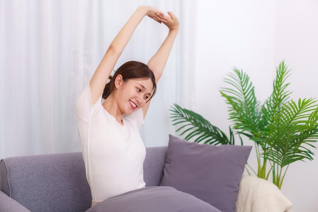 Lifestyle in living room concept Asian woman sitting on couch to stretching for relaxation