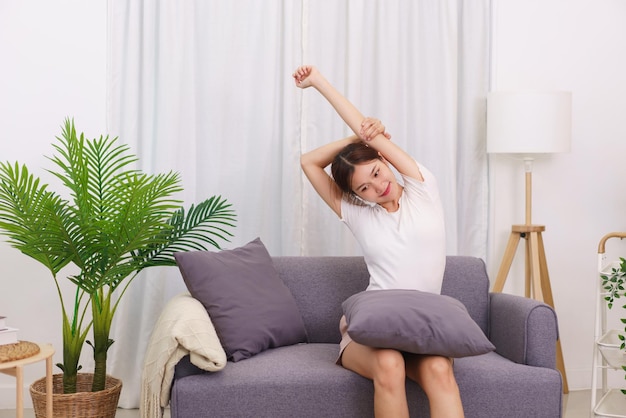 Lifestyle in living room concept Asian woman sitting on couch to stretching for relaxation