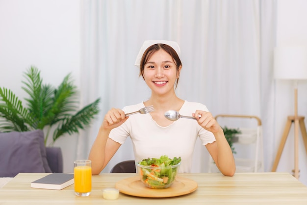 Lifestyle in living room concept Young Asian woman eating vegetable salad and orange juice