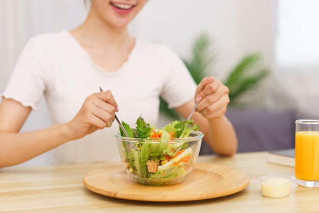 Lifestyle in living room concept Young Asian woman mixing vegetable salad in bowl for breakfast