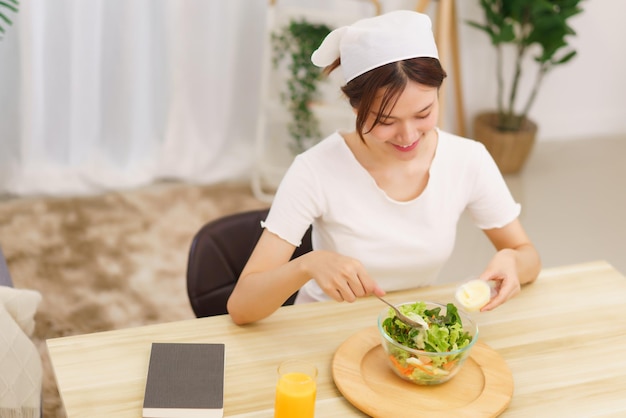 Lifestyle in living room concept Young Asian woman mixing vegetable salad with salad dressing