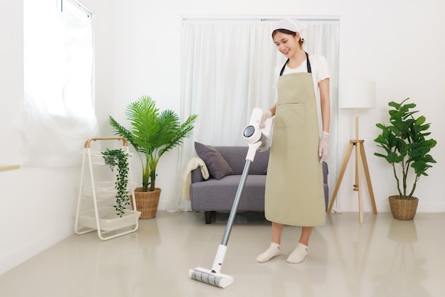 Lifestyle in living room concept Young Asian woman using vacuum cleaner to cleaning the floor