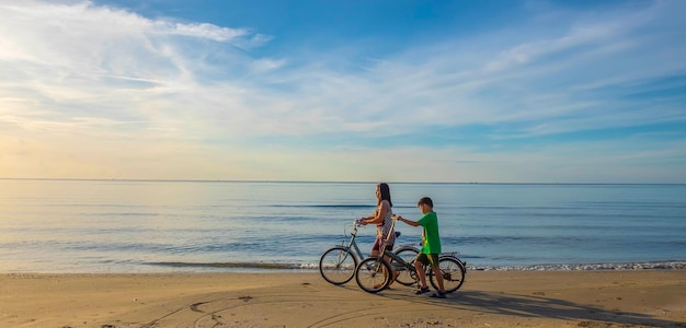 The lifestyle of a mother and son family on a bicycle at the sandy beach by the sea