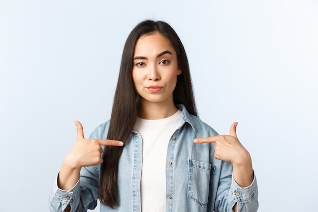 Lifestyle, people emotions and beauty concept. Sassy and confident asian girl pointing herself, promote personal services as freelancer during coronavirus pandemic, show-off or brag