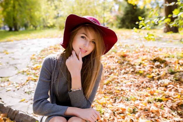 Lifestyle photo of fashionable blonde woman with natural makeup posing in red hat