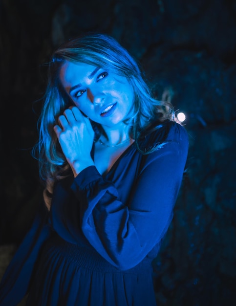 Lifestyle portrait of a caucasian girl in a cave with blue led light