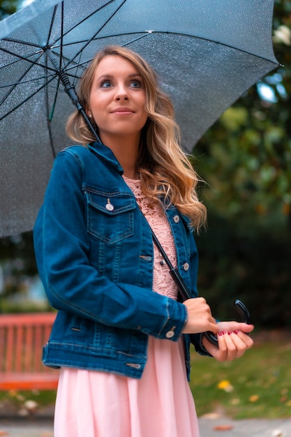 Lifestyle, portrait of a young blond Caucasian woman under an umbrella