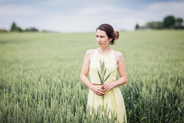 Lifestyle portrait of young stylish woman walking by wheat field