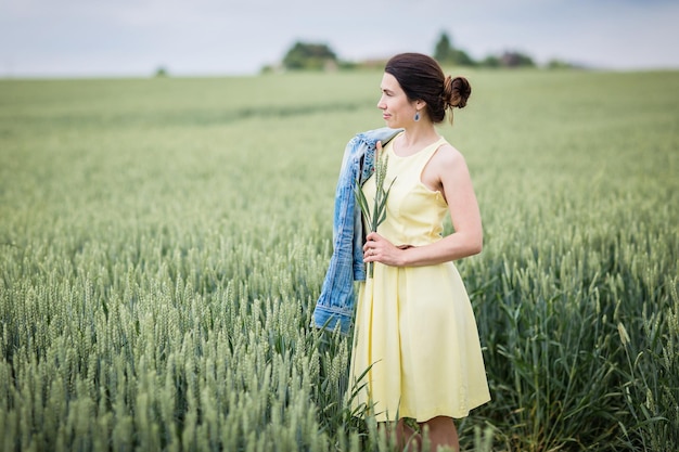 Lifestyle portrait of young stylish woman walking by wheat field