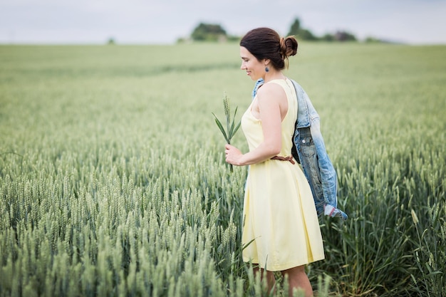 Lifestyle portrait of young stylish woman walking by wheat field