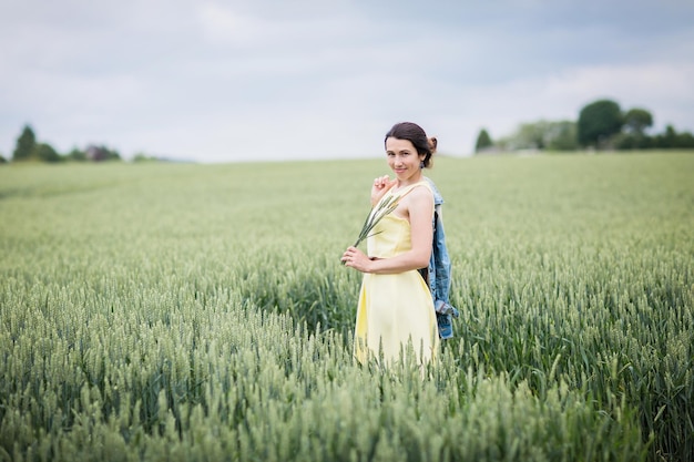 Lifestyle portrait of young stylish woman walking by wheat field