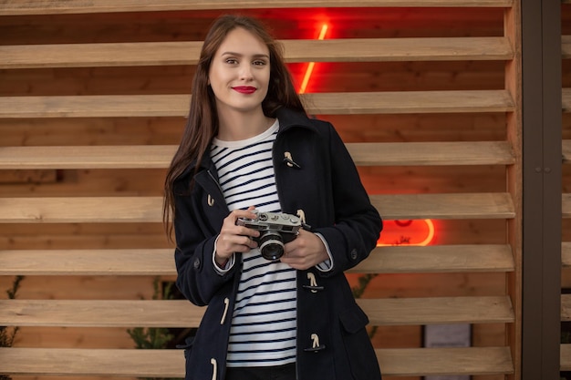 Lifestyle portrait of young stylish woman walking on street, with camera, smiling enjoy weekends, make a photo of her travel, old retro photocamera, vintage