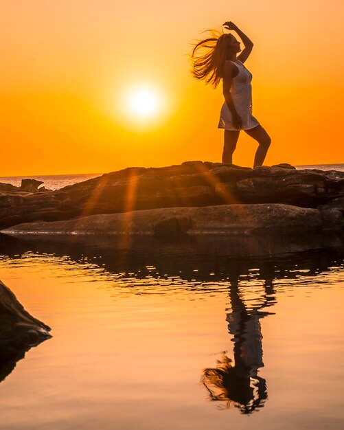 Photo lifestyle, silhouette of a young blonde on the coast at a sunset