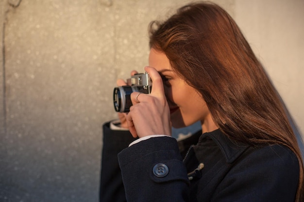 Lifestyle sunny fashion portrait of young stylish woman walking on street, with camera, smiling enjoy weekends, make a photo of her travel, old retro photocamera, vintage