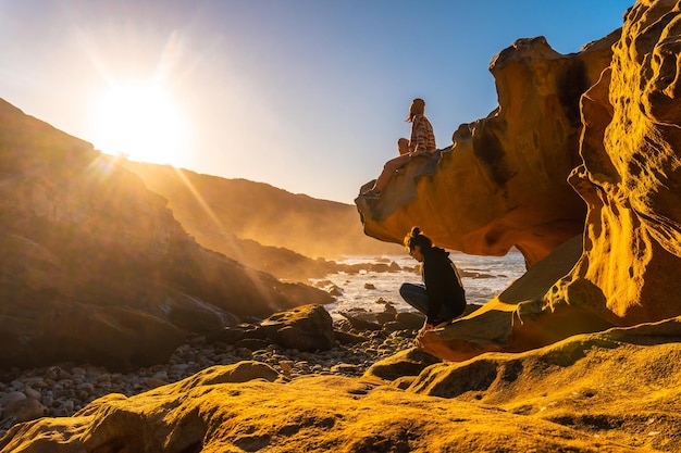 Lifestyle of two friends at sunset in the cove of stones in the Jaizkibel mountain